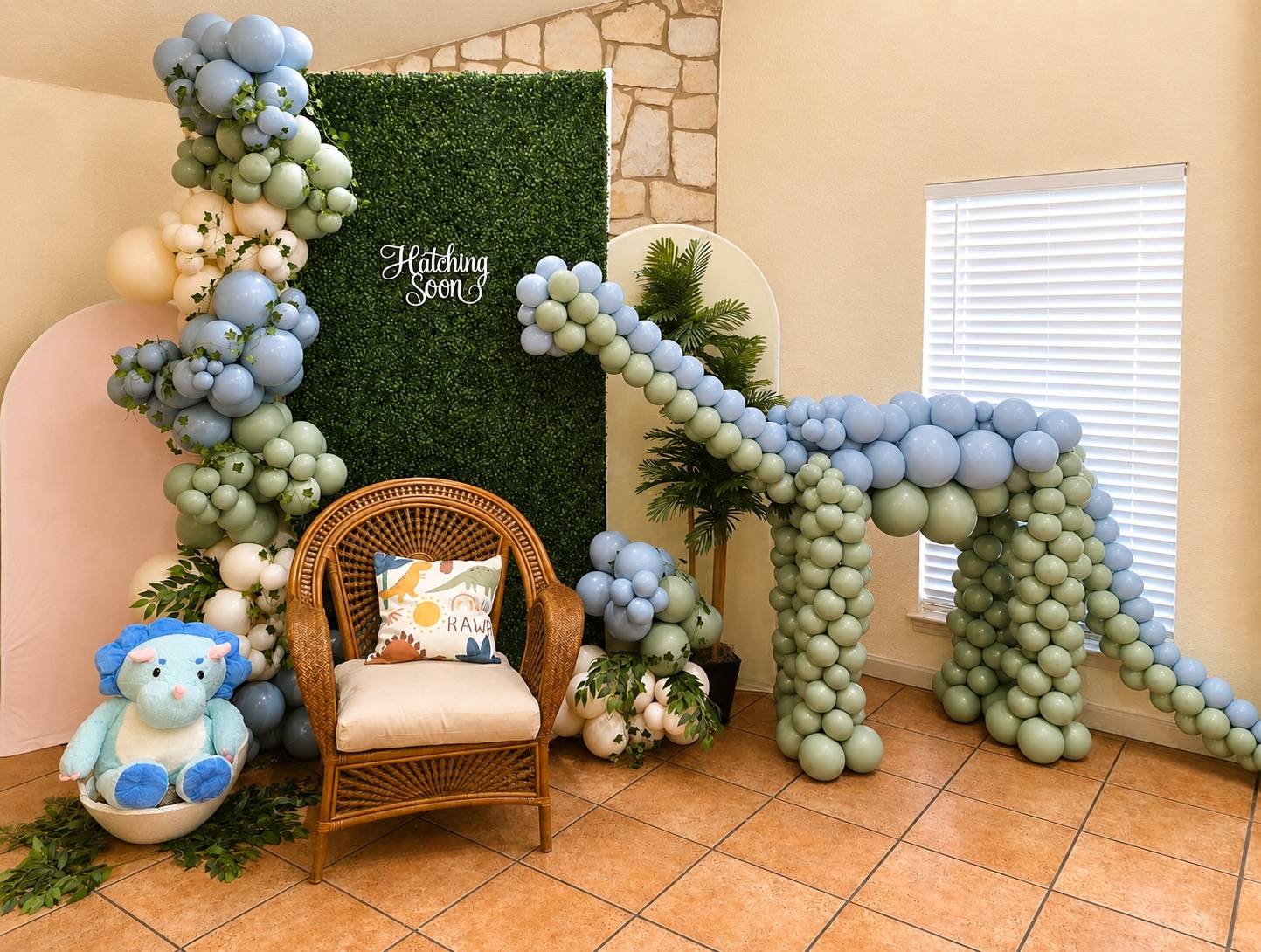 Blue, sage, and ivory dinosaur balloon installation for a baby celebration