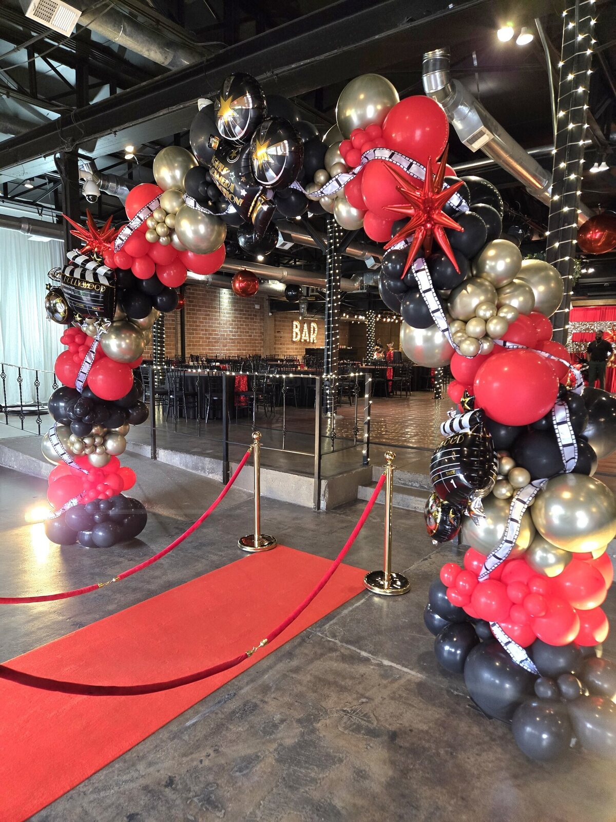 Red carpet and large black, red, and gold balloon installation