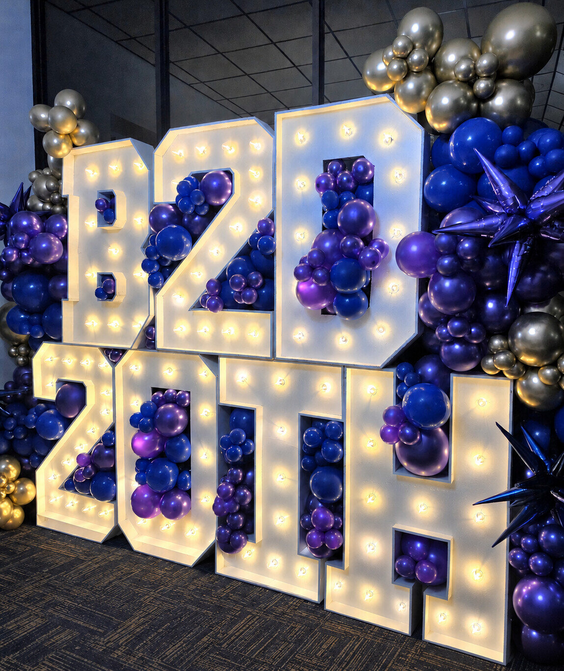 Illuminated 2024 marquee numbers surrounded by jewel-tone balloons